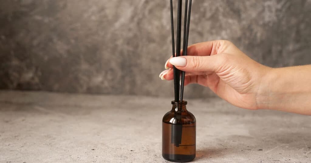 15 Best Reed Diffusers for Bathroom: A Buying Guide 30 lady removing reed diffuser sticks