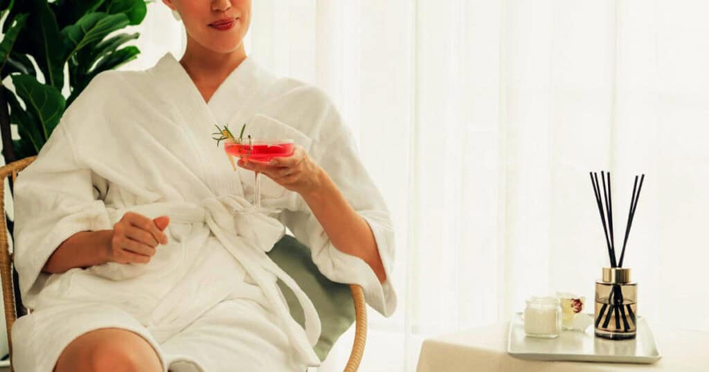 Budget vs Luxury Reed Diffusers: Are Premium Brands Really Worth It? 22 lady wearing bathrobe enjoying drinks with reed diffuser on the table