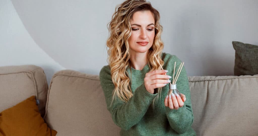 Budget vs Luxury Reed Diffusers: Are Premium Brands Really Worth It? 26 lady wearing green sweater holding a reed diffuser bottle